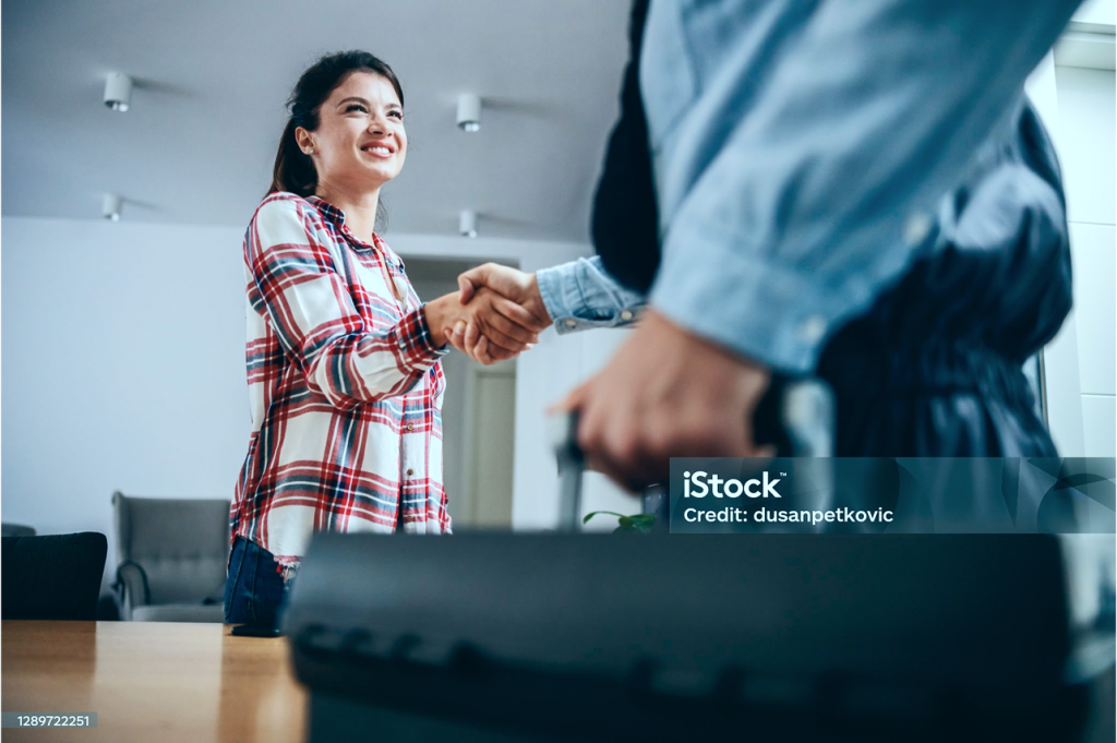 Ein Handwerker schüttelt die Hand einer lächelnden Kundin